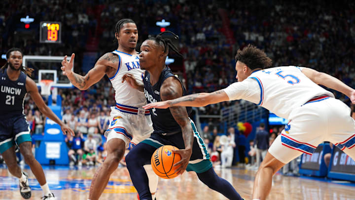Nov 19, 2024; Lawrence, Kansas, USA; North Carolina-Wilmington Seahawks guard Elijah Jamison (2) drives against Kansas Jayhawks guard Shakeel Moore (0) and guard Zeke Mayo (5) during the first half at Allen Fieldhouse. Mandatory Credit: Jay Biggerstaff-Imagn Images