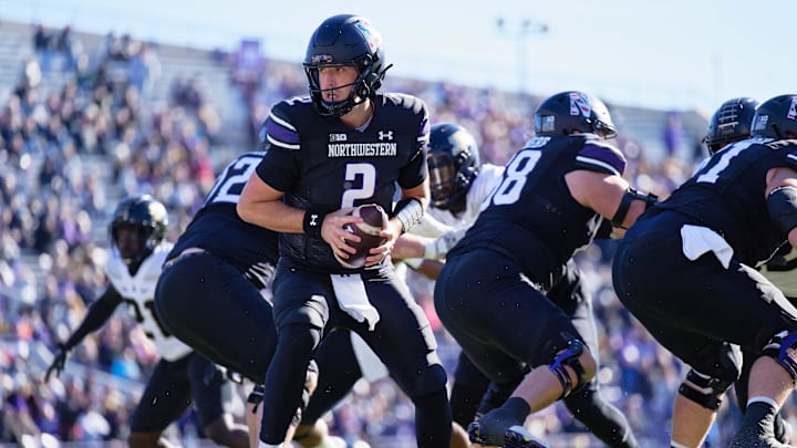 Nov 18, 2023; Evanston, Illinois, USA;  Northwestern Wildcats quarterback Ben Bryant (2) hands off the ball as Josh Priebe and the NU offensive line blocks against the Purdue Boilermakers at Ryan Field. Mandatory Credit: Jamie Sabau-Imagn Images