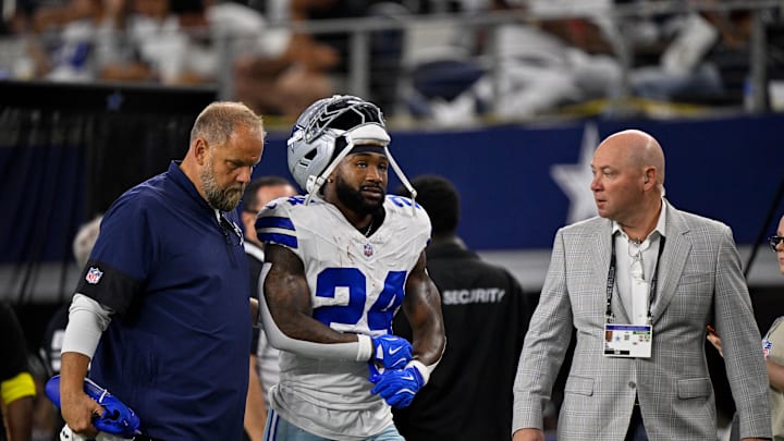 Sep 28, 2025; Arlington, Texas, USA; Dallas Cowboys running back Miles Sanders (24) walks off the field with team staff during the game between the Dallas Cowboys and the Green Bay Packers at AT&T Stadium. Mandatory Credit: Jerome Miron-Imagn Images