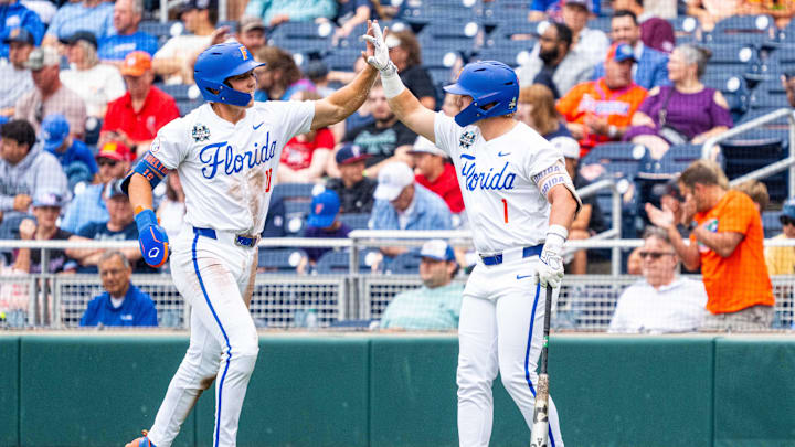 Jun 19, 2024; Omaha, NE, USA; Florida Gators shortstop Colby Shelton (10) and third baseman Dale Thomas (1) celebrate after Shelton scores a run against the Kentucky Wildcats during the first inning at Charles Schwab Field Omaha. Mandatory Credit: Dylan Widger-Imagn Images