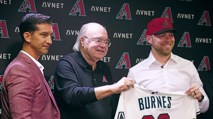 Diamondbacks general manager Mike Hazen (L-R) and managing general partner Ken Kendrick hold a jersey with new starting pitcher Corbin Burnes during an introductory press conference at Chase Field.