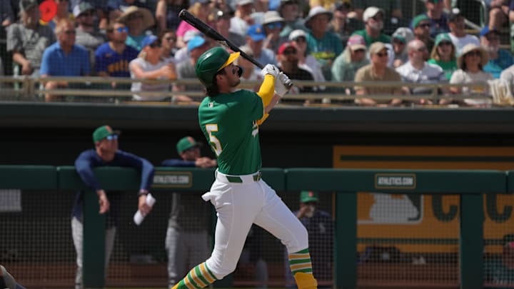 Mar 17, 2025; Mesa, Arizona, USA; Oakland Athletics shortstop Jacob Wilson (5) hits a solo home run against the Seattle Mariners in the third inning at Hohokam Stadium. Mandatory Credit: Rick Scuteri-Imagn Images