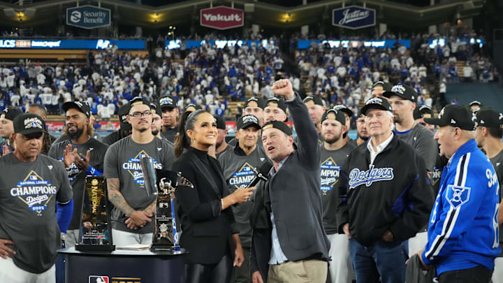 Oct 17, 2025; Los Angeles, California, USA; Los Angeles Dodgers president of baseball operations Andrew Friedman is interviewed by TBS reporter Lauren Shehadi as owner Mark Walter and president Stan Kasten watch after game four of the NLCS round for the 2025 MLB playoffs against the Milwaukee Brewers at Dodger Stadium. Mandatory Credit: Kirby Lee-Imagn Images