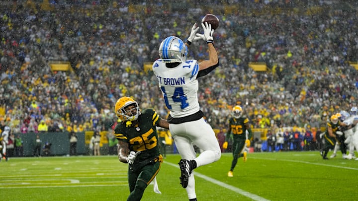 Nov 3, 2024; Green Bay, Wisconsin, USA;  Detroit Lions wide receiver Amon-Ra St. Brown (14) catches a pass in front of Green Bay Packers cornerback Keisean Nixon (25) to score a touchdown during the second quarter at Lambeau Field. Mandatory Credit: Jeff Hanisch-Imagn Images