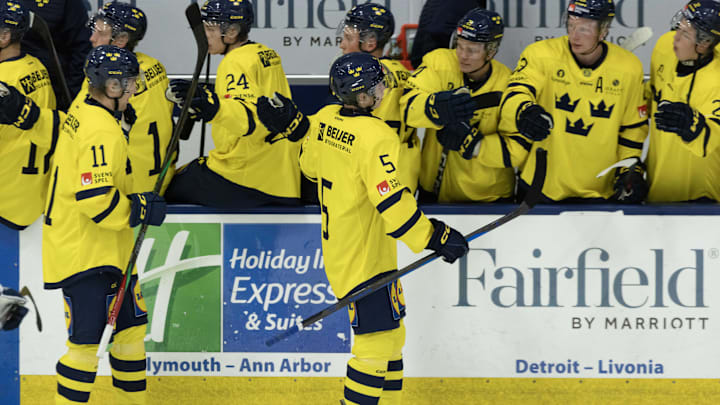 Aug 3, 2024; Plymouth, MI, USA; Sweden's defenseman Wilhelm Hallquisth (5) celebrates a goal against Finland with teammates on the bench during the second period of the 2024 World Junior Summer Showcase at USA Hockey Arena. Mandatory Credit: David Reginek-Imagn Images