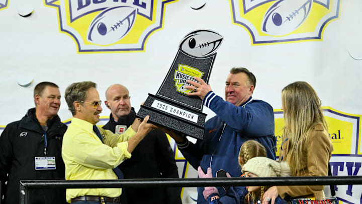 Dec 30, 2025; Nashville, TN, USA;  Illinois Fighting Illini head coach Bret Bielema hoist the trophy with Doug from Liberty Mutual against the Tennessee Volunteers during the second half at Nissan Stadium. Mandatory Credit: Steve Roberts-Imagn Images