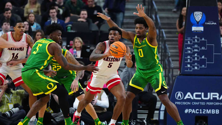 Mar 15, 2024; Las Vegas, NV, USA; Arizona Wildcats guard KJ Lewis (center) passes the ball against Oregon Ducks guard Jermaine Couisnard (5) and guard Kario Oquendo (0) at T-Mobile Arena. Mandatory Credit: Kirby Lee-Imagn Images