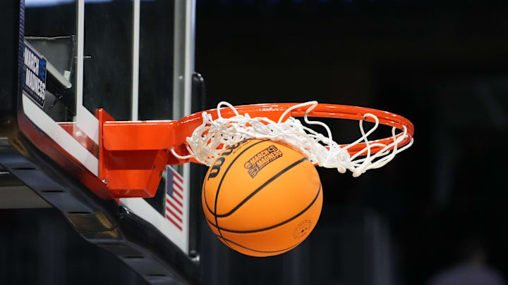 Mar 19, 2025; Wichita, KS, USA; A Wilson official NCAA Evo NXT basketball with the March Madness logo approaches the rim and the net at Intrust Bank Arena. Mandatory Credit: Kirby Lee-Imagn Images
