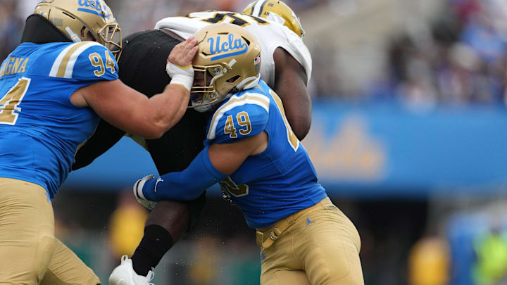 Sep 10, 2022; Pasadena, California, USA; UCLA Bruins defensive lineman Dovid Magna (94) and linebacker Carson Schwesinger (49) tackle Alabama State Hornets running back Marcus II Harris (26) in the second half at Rose Bowl. Mandatory Credit: Kirby Lee-Imagn Images