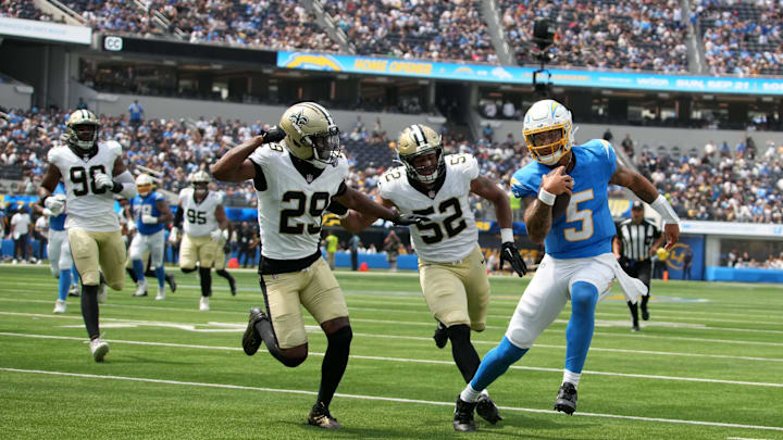 Aug 10, 2025; Inglewood, California, USA; Los Angeles Chargers quarterback Trey Lance (5) carries the ball against New Orleans Saints cornerback Quincy Riley (29) and linebacker D'Marco Jackson (52) in the first half at SoFi Stadium. Mandatory Credit: Kirby Lee-Imagn Images
