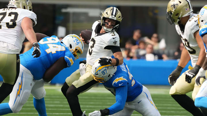 Aug 10, 2025; Inglewood, California, USA; New Orleans Saints quarterback Jake Haener (3) is pressured by Los Angeles Chargers defensive tackle TeRah Edwards (94) and linebacker Garmon Randolph (97) in the second half at SoFi Stadium. Mandatory Credit: Kirby Lee-Imagn Images