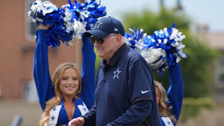 Dallas Cowboys owner Jerry Jones walks past cheerleaders at training camp opening ceremonies in Oxnard.