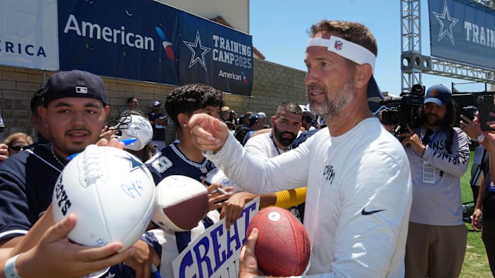 Dallas Cowboys coach Brian Schottenheimer signs autographs at training camp in Oxnard.