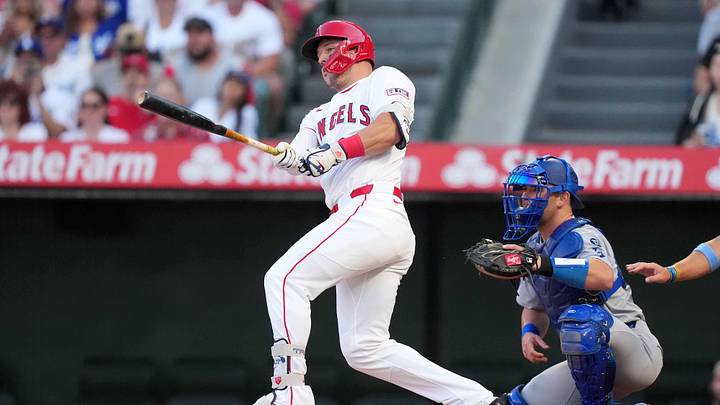 Aug 12, 2025; Anaheim, California, USA; Los Angeles Angels designated hitter Mike Trout (27) hits a single in the first inning as Los Angeles Dodgers catcher Dalton Rushing (68) watches  at Angel Stadium. Mandatory Credit: Kirby Lee-Imagn Images