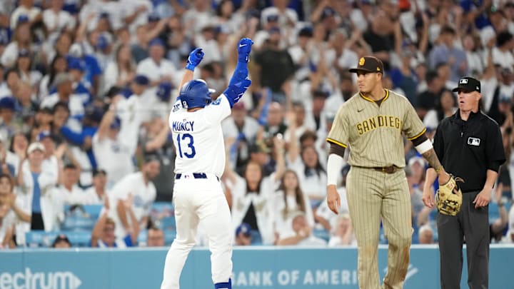 Jun 18, 2025; Los Angeles, California, USA; Los Angeles Dodgers third baseman Max Muncy (13) gestures after hitting a triple in the fifth inning as San Diego Padres third baseman Manny Machado (13) watches at Dodger Stadium. Mandatory Credit: Kirby Lee-Imagn Images