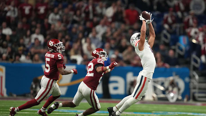 Dec 28, 2023; San Antonio, TX, USA; Arizona Wildcats wide receiver Tetairoa McMillan (4) catches the ball against Oklahoma Sooners defensive back Woodi Washington (5) and defensive back Peyton Bowen (22) in the fist half of the Alamo Bowl at Alamodome. Mandatory Credit: Kirby Lee-Imagn Images