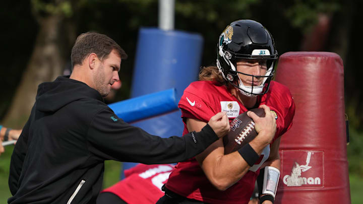 Oct 17, 2024; Watford, United Kingdom; Jacksonville Jaguars quarterback Trevor Lawrence (16) carries the ball against offensive coordinator Press Taylor during practice at The Grove. Mandatory Credit: Kirby Lee-Imagn Images