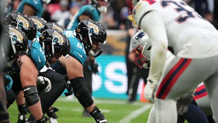 Oct 20, 2024; London, United Kingdom; Helmets at the line fo scrimmage as Jacksonville Jaguars center Mitch Morse (65) snaps the ball against the New England Patriots in the second half of an NFL International Series game at Wembley Stadium. Mandatory Credit: Kirby Lee-Imagn Images