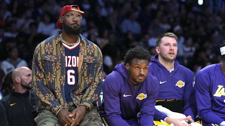 Oct 24, 2025; Los Angeles, California, USA; Los Angeles Lakers forward LeBron James (left), guard Bronny James (center) and guard Luka Doncic watch from the bench in the first half against the Minnesota Timberwolves at Crypto.com Arena. Mandatory Credit: Kirby Lee-Imagn Images