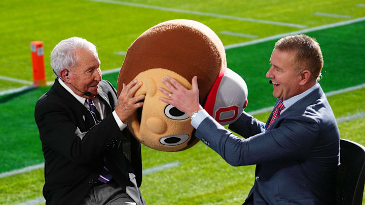 Jan 1, 2025; Pasadena, California, USA; Lee Corso (left) wears a Buckeyes mascot head as Kirk Herbstreit watches at Rose Bowl Stadium. Mandatory Credit: Kirby Lee-Imagn Images