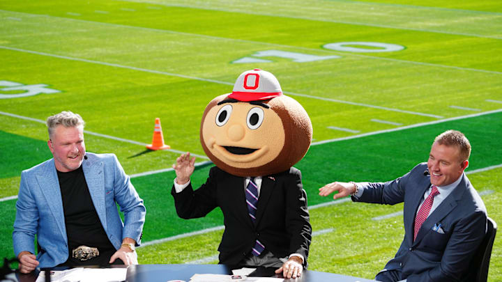 Jan 1, 2025; Pasadena, California, USA; Lee Corso (center) wears a Buckeyes mascot head  as Pat McAfee (left) and Kirk Herbstreit (right) watch at Rose Bowl Stadium. Mandatory Credit: Kirby Lee-Imagn Images
