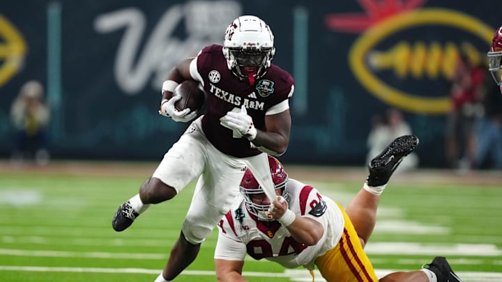 Dec 27, 2024; Las Vegas, NV, USA; Texas A&M Aggies wide receiver Micah Tease (4) carries the ball against Southern California Trojans defensive tackle Kobe Pepe (94) in the second half at Allegiant Stadium. Mandatory Credit: Kirby Lee-Imagn Images