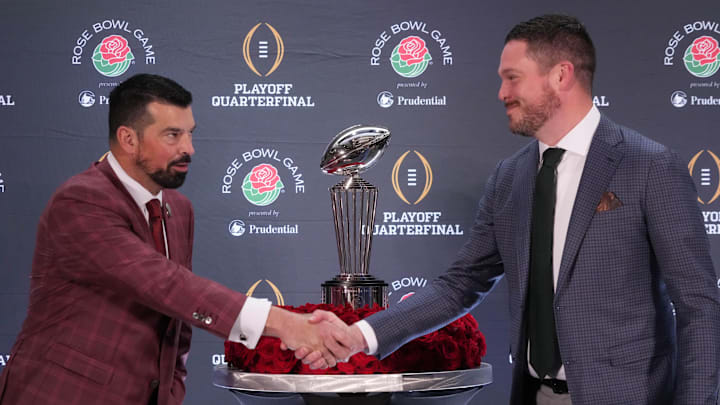 Dec 31, 2024; Los Angeles, California, USA; Ohio State Buckeyes head coach Ryan Day (left) and Oregon Ducks head coach Dan Lanning shake hands with the Leishman Trophy as a backdrop during the Rose Bowl head coaches press conference at Sheraton Grand LA. Mandatory Credit: Kirby Lee-Imagn Images