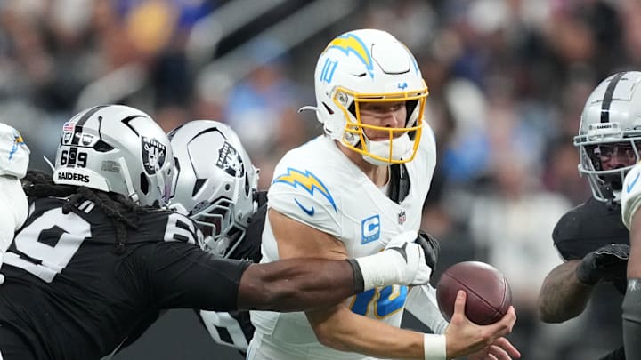 Jan 5, 2025; Paradise, Nevada, USA; Los Angeles Chargers quarterback Justin Herbert (10) is sacked by Las Vegas Raiders defensive tackle Adam Butler (69) in the first half at Allegiant Stadium. Mandatory Credit: Kirby Lee-Imagn Images
