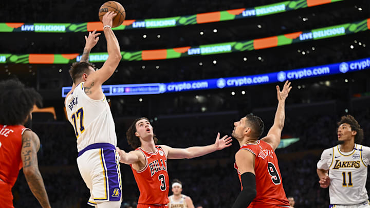 Mar 22, 2025; Los Angeles, California, USA; Los Angeles Lakers guard Luka Doncic (77) passes against Chicago Bulls guard Josh Giddey (3) and center Nikola Vucevic (9) during the first half at Crypto.com Arena. Mandatory Credit: Jonathan Hui-Imagn Images