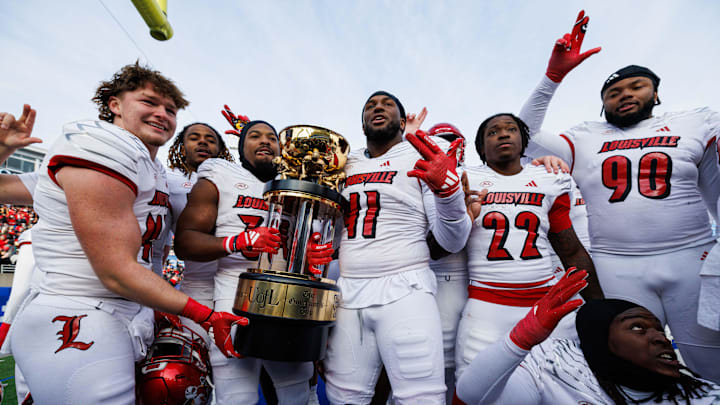 Nov 30, 2024; Lexington, Kentucky, USA; Louisville Cardinals defensive lineman Ramon Puryear (41) and Louisville Cardinals defensive back Jathan Hatch (31) hold up the Governor’s Cup trophy after winning against the Kentucky Wildcats at Kroger Field. Mandatory Credit: Jordan Prather-Imagn Images