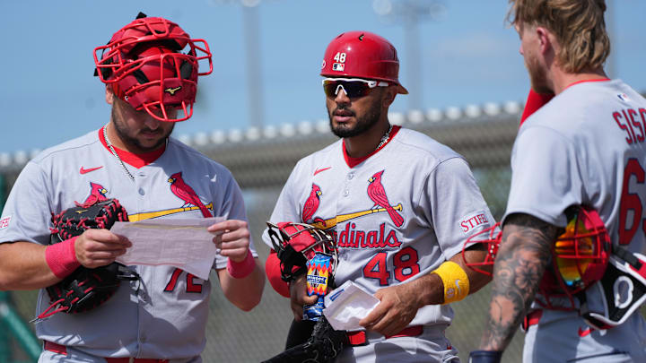 Feb 17, 2025; Jupiter, FL, USA;  St. Louis Cardinals catcher Jimmy Crooks (72), catcher Ivan Herrera (48) and catcher Chance Sisco (65) look over the schedule at spring training. Mandatory Credit: Jim Rassol-Imagn Images
