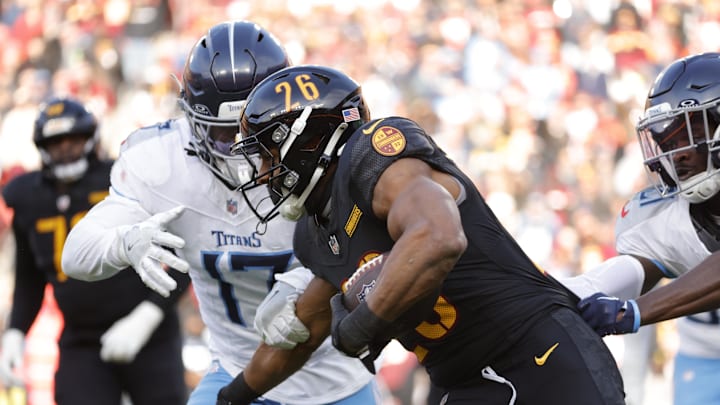 Dec 1, 2024; Landover, Maryland, USA; Washington Commanders running back Jeremy McNichols (26) carries the ball as Tennessee Titans linebacker Jerome Baker (17) and Titans cornerback Roger McCreary (21) defend during the first half at Northwest Stadium. Mandatory Credit: Amber Searls-Imagn Images