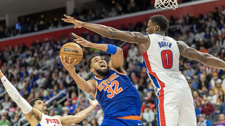 Apr 27, 2025; Detroit, Michigan, USA; New York Knicks center Karl-Anthony Towns (32) drives to the basket between Detroit Pistons center Jalen Duren (0) and forward Tobias Harris (12) during the second quarter of game four of first round for the 2025 NBA Playoffs at Little Caesars Arena. Mandatory Credit: David Reginek-Imagn Images