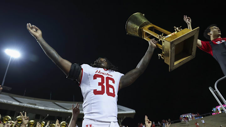 Sep 6, 2025; Houston, Texas, USA; Houston Cougars linebacker Jalen Garner (36) raises the Bayou Bucket trophy after a win against the Rice Owls at Rice Stadium. Sep 6, 2025; Houston, Texas, USA; Houston Cougars linebacker Jalen Garner (36) raises the Bayou Bucket trophy after a win against the Rice Owls at Rice Stadium.