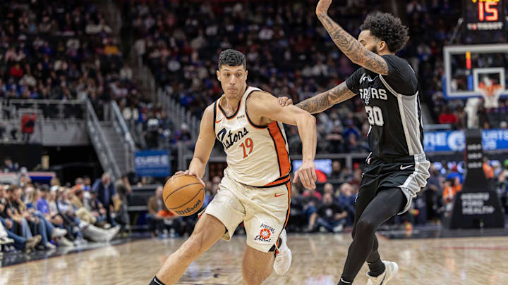 Mar 25, 2025; Detroit, Michigan, USA; Detroit Pistons forward Simone Fontecchio (19) moves the ball up court as San Antonio Spurs forward Julian Champagnie (30) defends during the first half at Little Caesars Arena. Mandatory Credit: David Reginek-Imagn Images