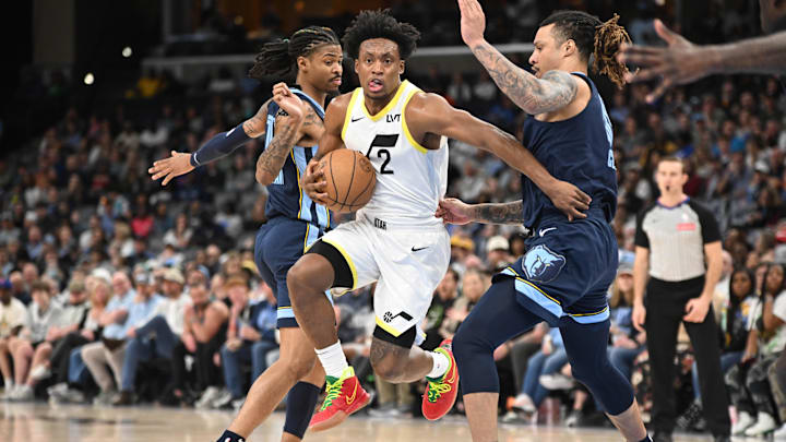 Mar 12, 2025; Memphis, Tennessee, USA; Utah Jazz point guard Collin Sexton (2) jumps through defenders Memphis Grizzlies point guard Ja Morant (12) (left) and Memphis Grizzlies power forward Brandon Clarke (15) (right) in the third quarter at FedExForum. Mandatory Credit: Matthew Smith-Imagn Images