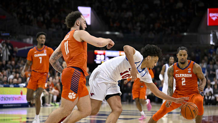 Feb 22, 2025; Dallas, Texas, USA; SMU Mustangs guard AJ George (10) moves the ball past Clemson Tigers guard Jaeden Zackery (11) during the second half at Moody Coliseum.