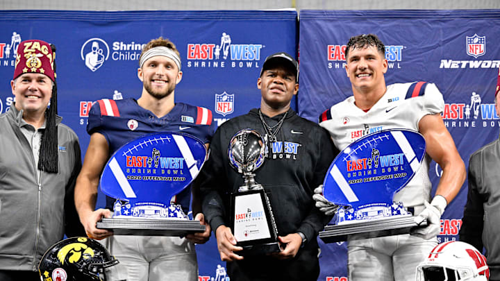 Jan 27, 2026; Frisco, TX, USA; (from left) West quarterback Mark Gronowski (11) and West head coach Lunda Wells and East edge rusher Mason Reiger (22) pose with their trophies after the game at the Ford Center at the Star.  