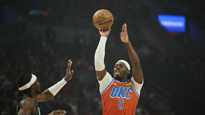 Nov 30, 2025; Portland, Oregon, USA; Oklahoma City Thunder guard Luguentz Dort (5) shoots a jump shot during the first half against Portland Trail Blazers forward Jerami Grant (9) at Moda Center. Mandatory Credit: Troy Wayrynen-Imagn Images