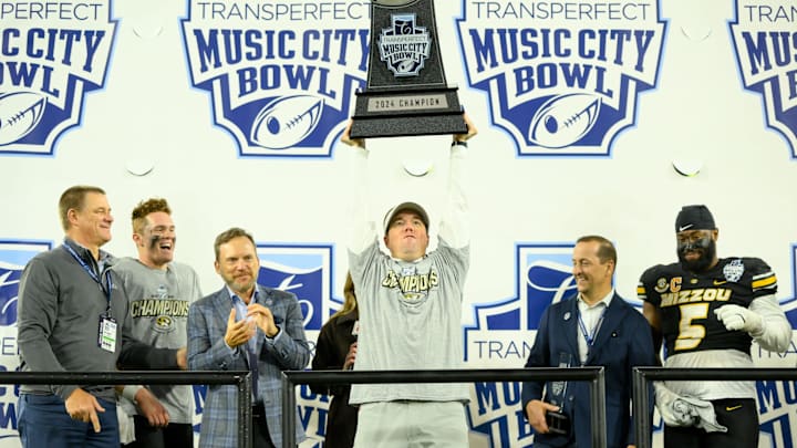 Dec 30, 2024; Nashville, TN, USA; Missouri Tigers head coach Eliah Drinkwitz holds the trophy up above his head against the Iowa Hawkeyes during the trophy presentation at Nissan Stadium. Mandatory Credit: Steve Roberts-Imagn Images Dec 30, 2024; Nashville, TN, USA; Missouri Tigers head coach Eliah Drinkwitz holds the trophy up above his head against the Iowa Hawkeyes during the trophy presentation at Nissan Stadium. Mandatory Credit: Steve Roberts-Imagn Images