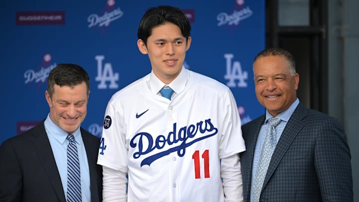 New Los Angeles Dodgers pitcher Roki Sasaki stands in between Andrew Friedman, president of baseball operations and manager Dave Roberts during an introductory press conference at Dodger Stadium.