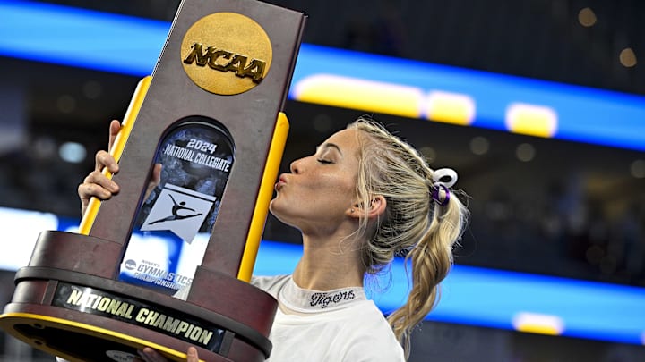 Apr 20, 2024; Fort Worth, TX, USA; LSU Tigers gymnast Olivia Dunne kisses the trophy after the LSU Tigers gymnastics team wins the national championship in the 2024 Womens National Gymnastics Championship at Dickies Arena. Mandatory Credit: Jerome Miron-Imagn Images