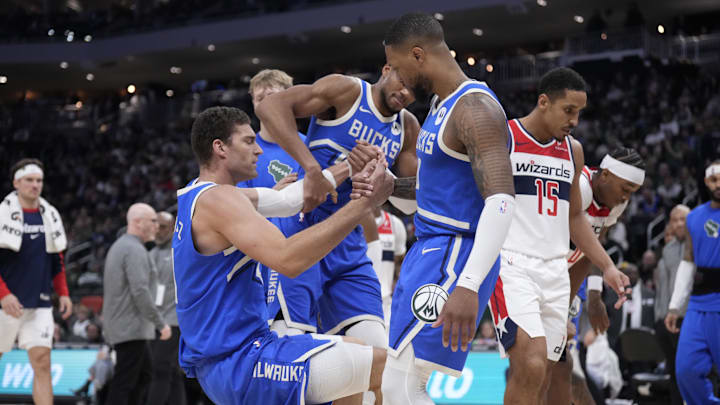 Nov 30, 2024; Milwaukee, Wisconsin, USA; Milwaukee Bucks forward Giannis Antetokounmpo (34) and Milwaukee Bucks guard Damian Lillard (0) help Milwaukee Bucks center Brook Lopez (11) up after colliding with Washington Wizards guard Jordan Poole (13) in the second half at Fiserv Forum. Mandatory Credit: Michael McLoone-Imagn Images