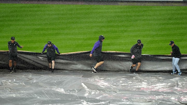 Members of the Coors Field grounds crew pull a tarp onto the field