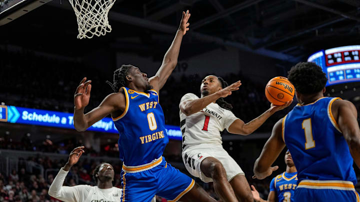 West Virginia Mountaineers center Eduardo Andre (0) blocks Cincinnati Bearcats guard Day Day Thomas (1) on his way to the basket in the second half of the NCAA basketball game between the Cincinnati Bearcats and the West Virginia Mountaineers at Fifth Third Arena in Cincinnati on Sunday, Feb. 2, 2025. The Bearcats lost, 63-50.