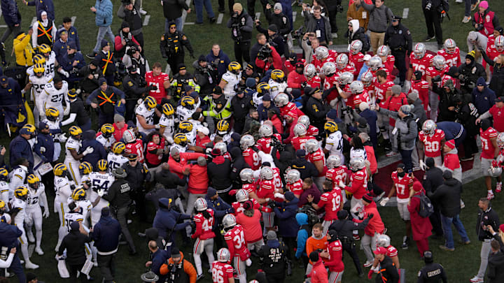 Players scrum at midfield following Saturday’s NCAA Division I football game between the Ohio State Buckeyes and the Michigan Wolverines.