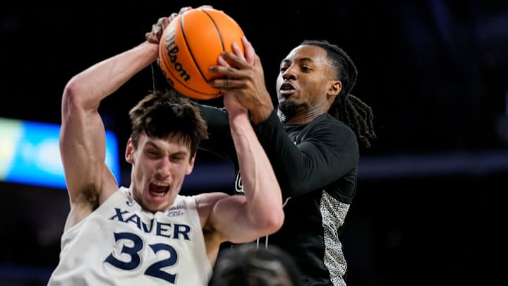 Xavier Musketeers forward Zach Freemantle (32) pulls in a rebound away from Cincinnati Bearcats guard Day Day Thomas (1) in the second half of the 92nd Annual Crosstown Shootout NCAA basketball game between the Cincinnati Bearcats and the Xavier Musketeers at Fifth Third Arena on the UC campus in Cincinnati on Saturday, Dec. 14, 2024. The Bearcats won 68-65.