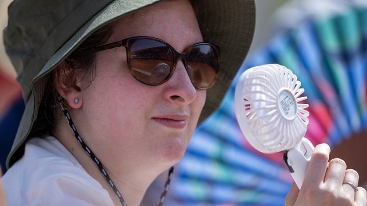 A spectator uses a fan to cool off at Stade Roland Garros A spectator uses a fan to cool off at Stade Roland Garros