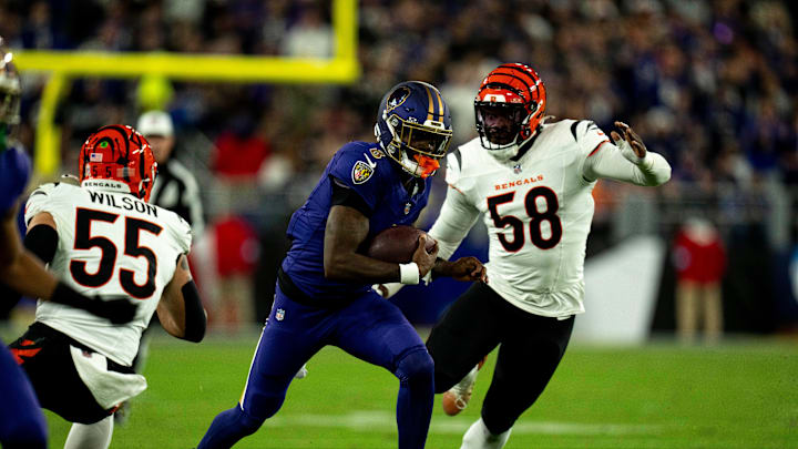 Baltimore Ravens quarterback Lamar Jackson (8) runs downfield for a first down as Cincinnati Bengals linebacker Logan Wilson (55) and Cincinnati Bengals defensive end Joseph Ossai (58) defend in the first quarter of the NFL game at M&T Banks Stadium in Baltimore on Thursday, Nov. 7, 2024.