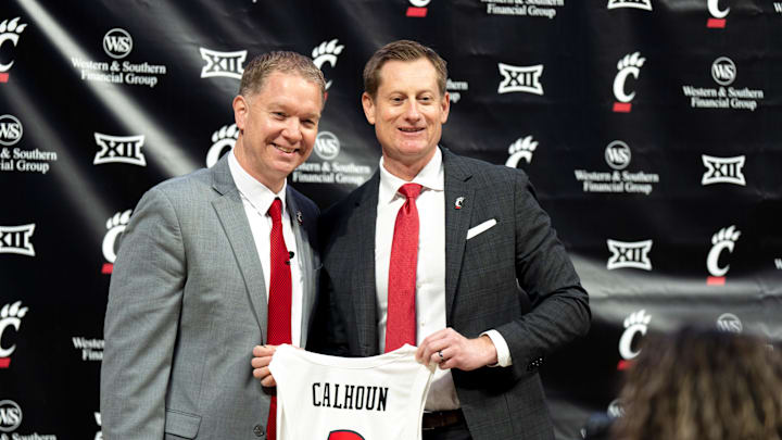 University of Cincinnati athletic director John Cunningham stands with Cincinnati head coach Jerrod Calhoun with a jersey as he is announced as the head men's basketball coach at Fifth Third Arena in Cincinnati on Wednesday, March 25, 2026.